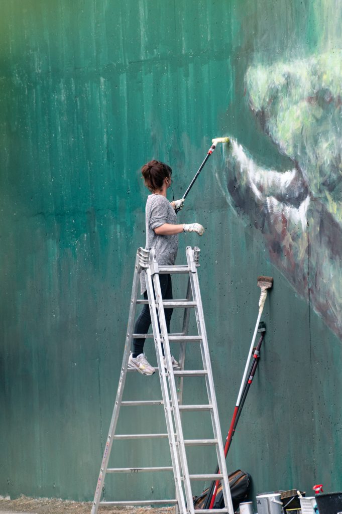 L'artiste animalière Sandrot sur une échelle en train de peindre une fresque à Toulouse 